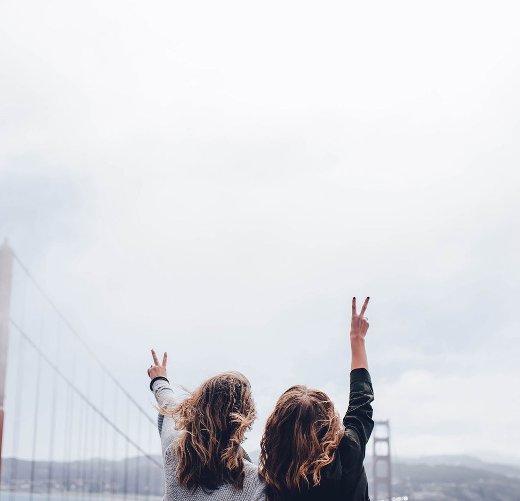 Two friends raising peace signs in front of the Golden Gate Bridge